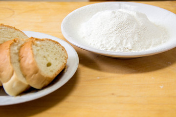 Slices of bread and wheat flour in a white plate on the table