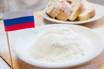 Close-up shot of russian flag and flour in a plate. Slices of bread on the background