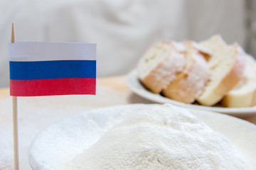 Close-up shot of russian flag and flour in a plate. Slices of bread on the background