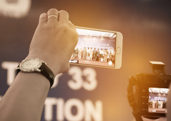 Blur of woman hands take photo or recording speaker with smart phone, camcorder mobile operator...