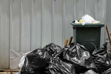 Green garbage bin with black garbage bags.