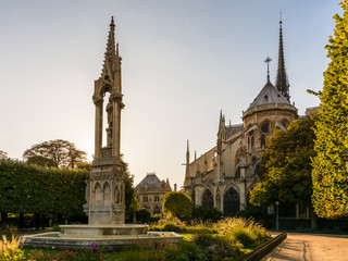 Obraz premium Rear view of Notre-Dame de Paris cathedral at sunset with the fountain of the Virgin in the foreground.