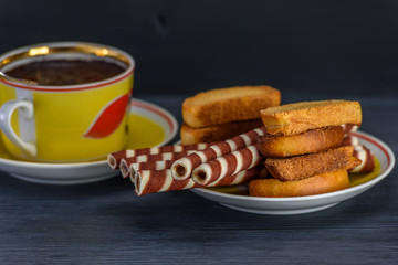 waffle rolls on a plate coffee mug on a dark background