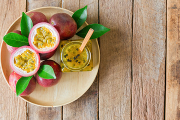 Homemade passion fruit jam in bottle on wood plate. Passion fruit jam on wood table in top view flat lay style with copy space. Fresh passion fruit and homemade jam on wood table in natural concept.