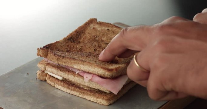 Cooking a rustic brie and ham sandwich with mustard sauce in an industrial style kitchen