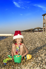 Little boy in Santa hat with toys on the beach