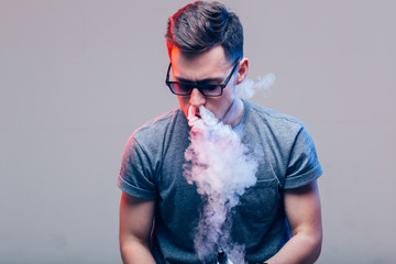 Men with beard in sunglasses vaping and releases a cloud of vapor in nose