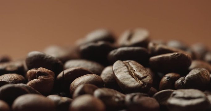 Pan close up video of freshly roasted coffee beans isolated on brown