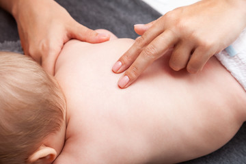Little baby receiving chiropractic treatment of her back - obrazy, fototapety, plakaty