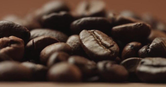 Pan close up video of freshly roasted coffee beans isolated on brown