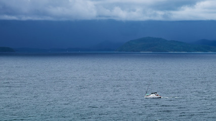 Boat at the sea with storm clouds and rain over sea on background.