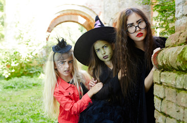 Three long-haired halloween girls peeking out of corner of neglected building