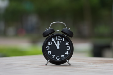 Retro alarm clock with five minutes to twelve o'clock.
