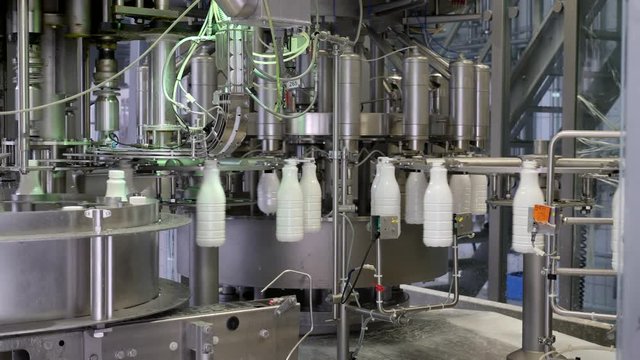 A moving shot of a milk production line, the bottles are filled with milk and then hermetically sealed