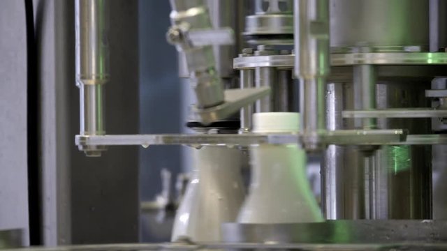 Footage of a milk production line, the bottles are filled with milk and then hermetically sealed...