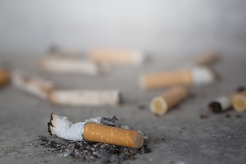 Cigarette butts on a gray background. Smoking is bad for your health.