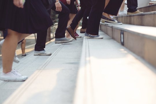 People And Businessman Legs Walking The Stairs In Modern City.