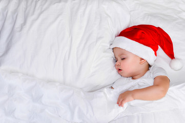 little baby lying on white linen in the Santa hat and clock show five minutes to eleven
