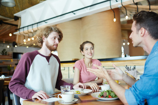 Group Of Friends Discussing Latest News Or Task For Seminar By Lunch In Cafeteria