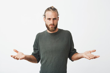 Handsome nordic man with beard and stylish hairdo spreads hands with cynical and mean expression...