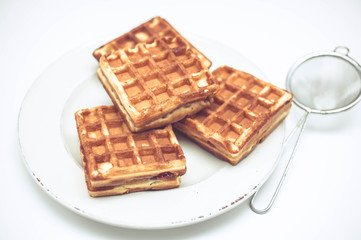 Belgian waffles with strawberry jam on white plate on light background. 