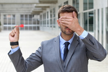 Blind businessman holding a dart 