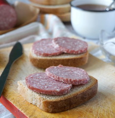 Sandwich with sausage and black tea with sugar