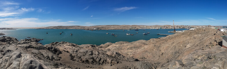 Panoramic view of Luderitz harbor and its rocky landscape with many boats and ships in the lagoon,...
