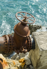 Big old water supply valve on the sea coast.