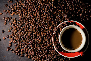 Hot coffee in red cup and coffee beans are the background.
