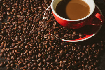 Hot coffee in red cup and coffee beans are the background.