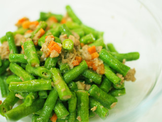 Thai local traditional homemade food: stir fried green string bean vegetable with chopped carrot and minced pork, with oyster sauce, served in glass bowl, close up perspective shot