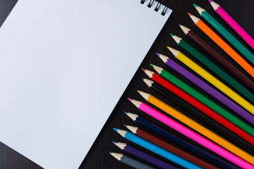 Multicolored pencils and a paper notepad