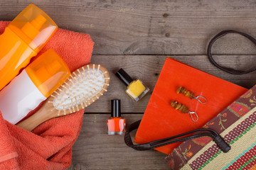 Beach accessories - hairbrush, orange towel, sun cream, lotion, beach bag, nail polish, a book on a...