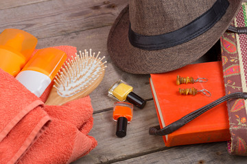 Beach accessories - hairbrush, orange towel, hat, sun cream, lotion, beach bag, nail polish, a book...