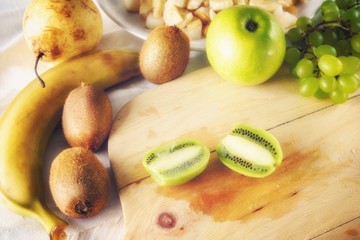 Ingredients for fruit salad. Cutting kiwi