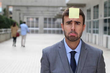 Sad businessman with a note on his forehead