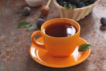 A cup of tea and plum on the table