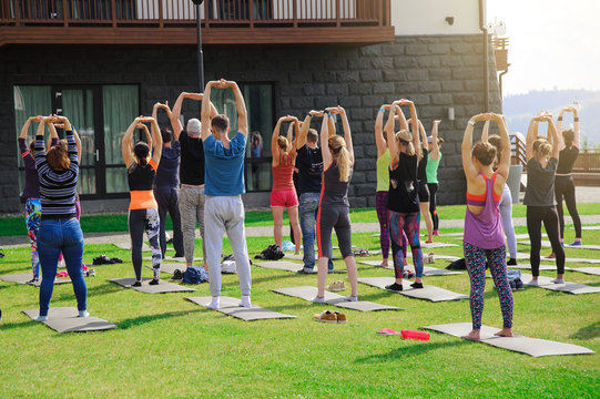 Group of adults attending a yoga class outside in yard