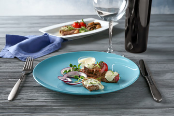 Sliced steak served with vegetables and white sauce on blue plate