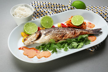 Plate with delicious fish, sauce and garnish on table