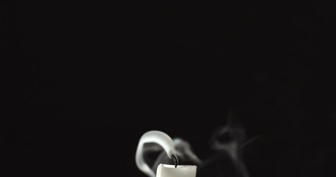 Candle blown out and white smoke rising up on black background