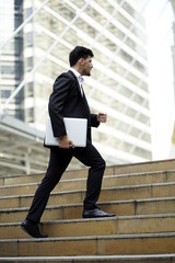 businessman walk to the ladder with laptop of success