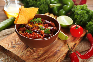 Chili con carne in bowl served with chips on kitchen table
