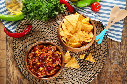 Chili con carne in bowl served with chips on kitchen table
