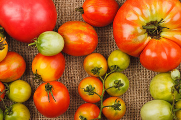 Set of different sorts of ripe tomatoes in the wooden tray