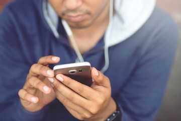 Always in touch. Cheerful handsome young man using Earphone his smart phone. 