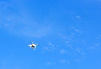 Flying drone with blue sky background controlled by professional photographer