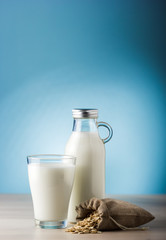 Glass of milk and sack of oats on a wooden table and blue background. daily food