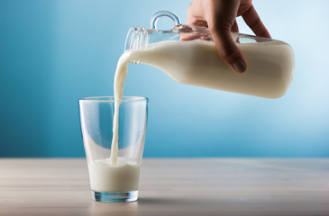 Hand of Female woman serving milk in a glass.